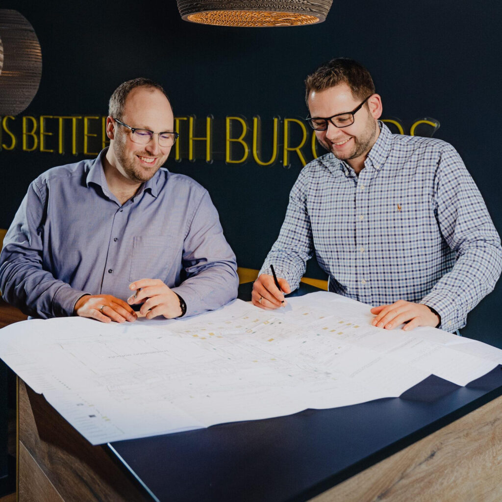 2 Männer unterschreiben auf einem Bauplan